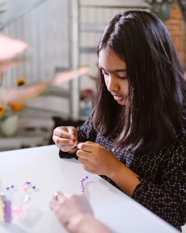 Girl threading a beaded bracelet