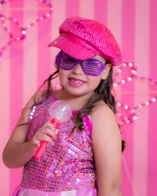 Girl in a pink sequin outfit singing into a microphone